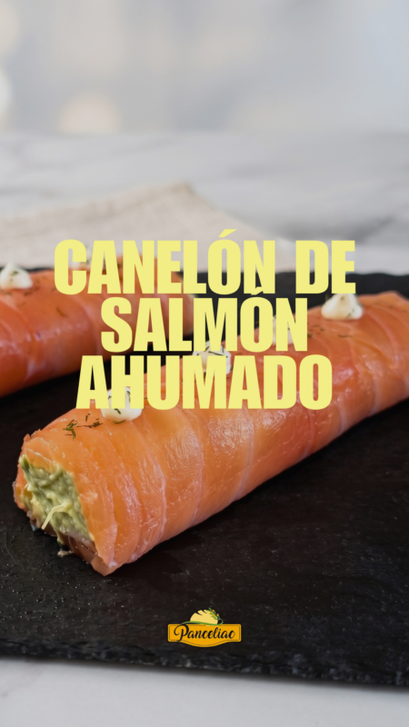 Canelón de salmón ahumado sin gluten relleno de aguacate, cortado y servido en una pizarra